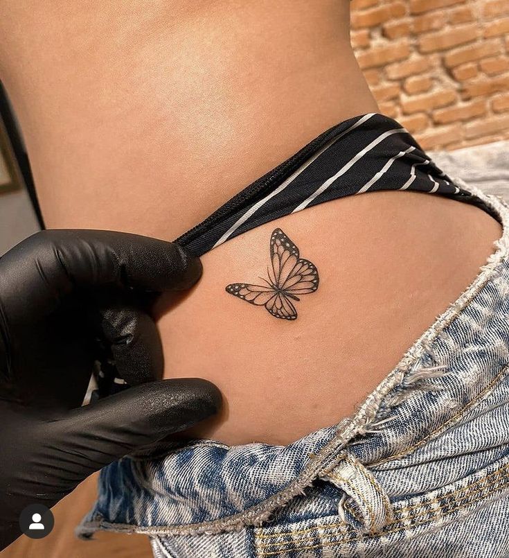 a woman's stomach with a small butterfly tattoo on the side of her belly