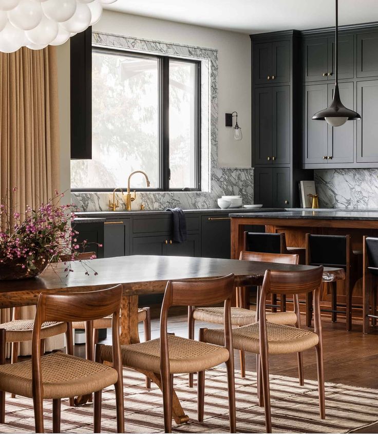 a dining room table and chairs in front of a kitchen with dark wood cabinetry