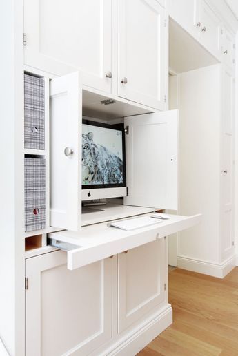 a computer monitor sitting on top of a white desk in a room with wooden floors