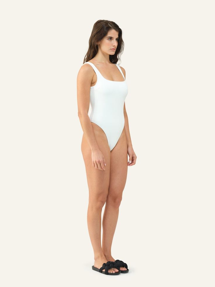 Minimal in design but far from basic, this one-piece must-have is both playful and alluring. White Second-skin Bodysuit With Lined Body, White Seamless Bodysuit With Minimal Stretch, Chic White Second-skin Swimwear, White Seamless Bodysuit For Summer, Chic White Second-skin Bodysuit, Chic White Seamless Bodysuit, White Scoop Neck Swimwear With Lined Body, White Fitted Scoop Neck Swimwear, White Second-skin One-piece Bodysuit