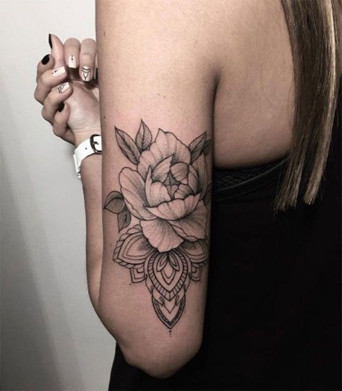 a woman's arm with a rose tattoo on the left side of her arm