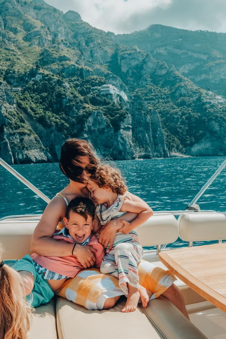 a woman and two children sitting on the back of a boat