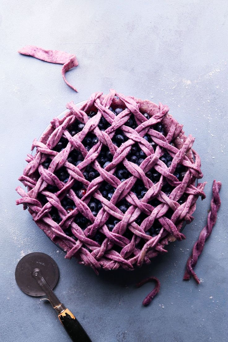 a blueberry pie sitting on top of a table next to a spatula and knife