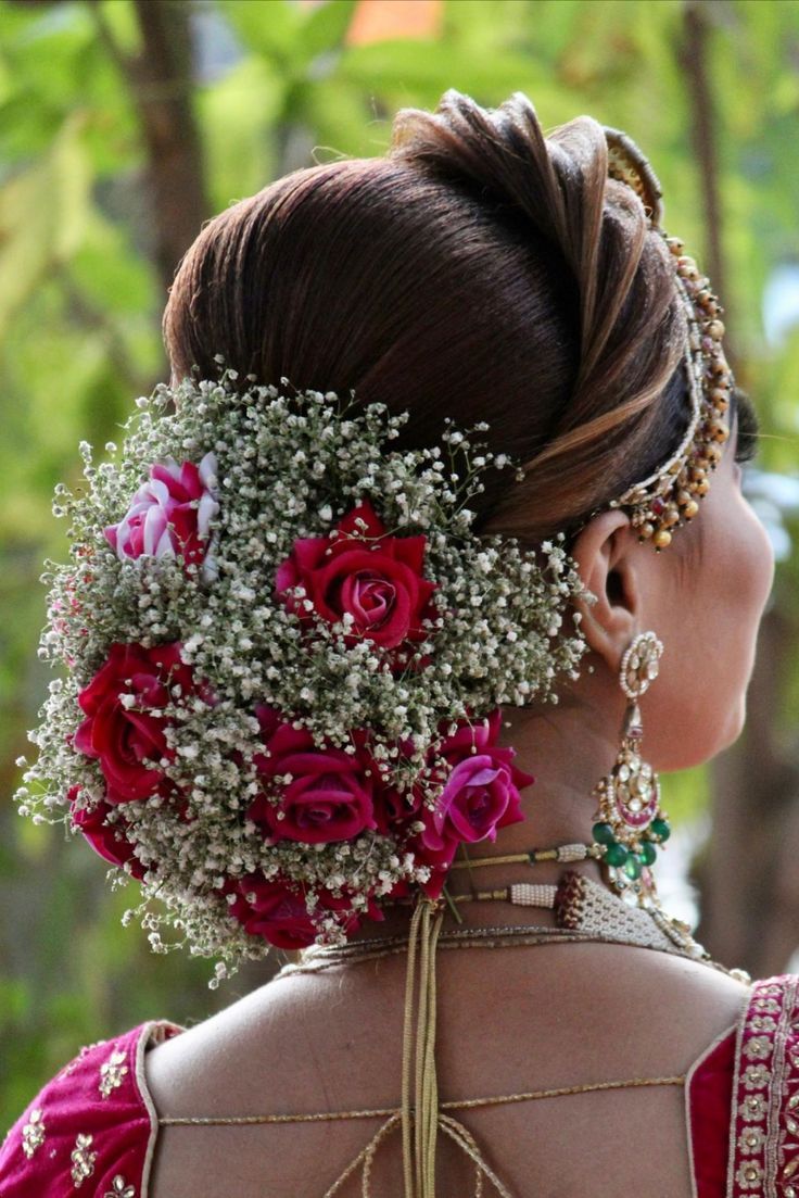 the back of a woman's head is adorned with flowers and baby's breath