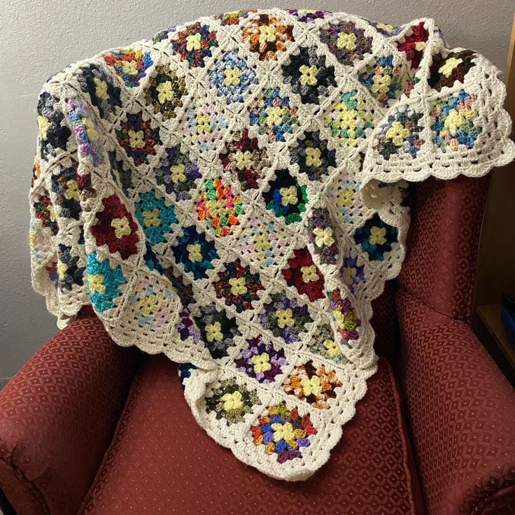 a crocheted granny's afghan sits on a red chair