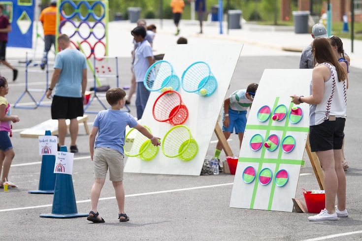 several people standing around with tennis rackets and balls painted on canvases in the parking lot