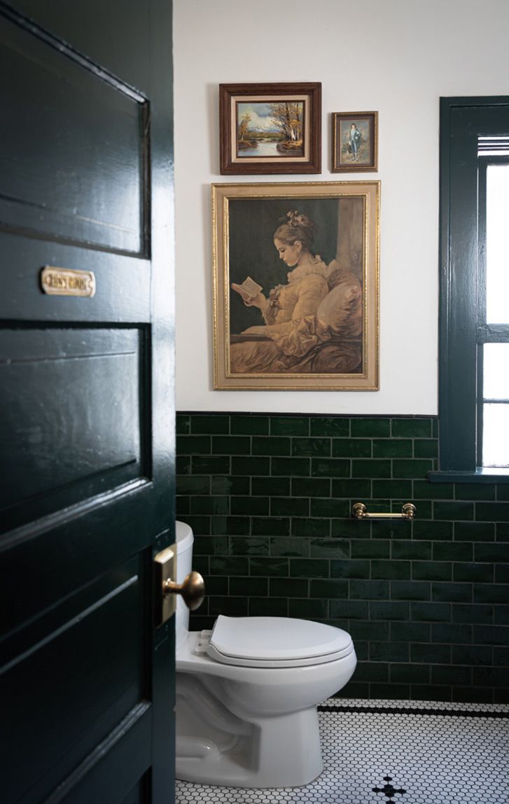 a white toilet sitting in a bathroom next to a painting on the wall above it