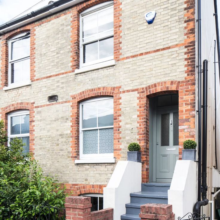 a brick house with white windows and blue steps