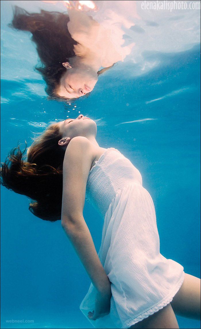 a woman in white shirt swimming under water