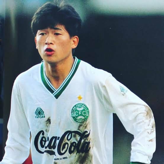 a young man holding a soccer ball on top of a field