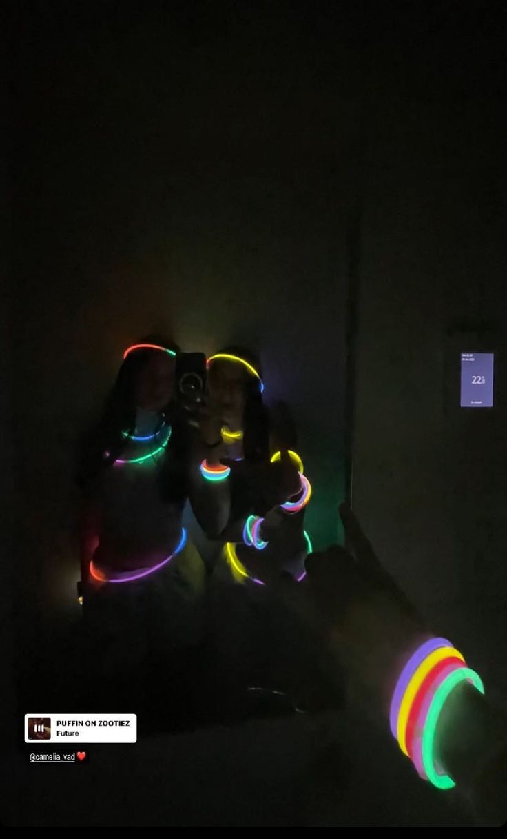 two people sitting in the dark with their arms around each other and glowing lights on them