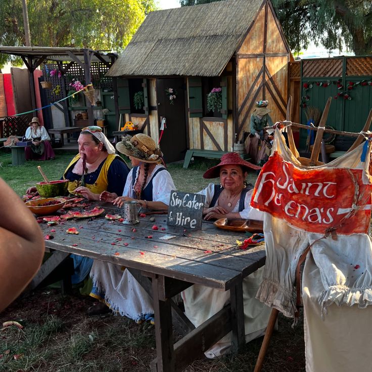 several people sitting at a picnic table eating food