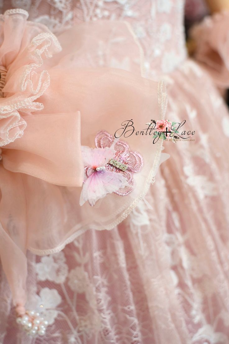 the back of a pink dress with flowers on it's chest and an attached brooch