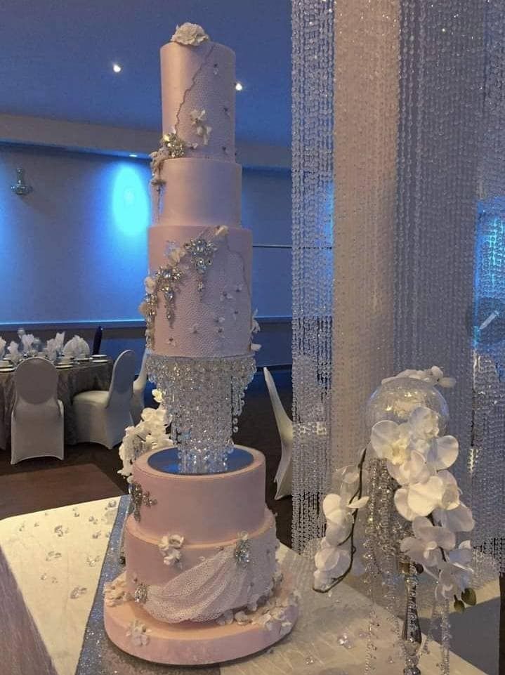 a three tiered wedding cake sitting on top of a table next to white flowers