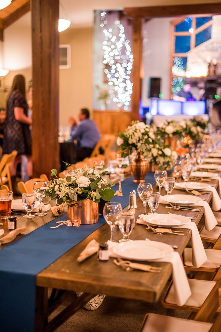 a long table set with place settings and flowers