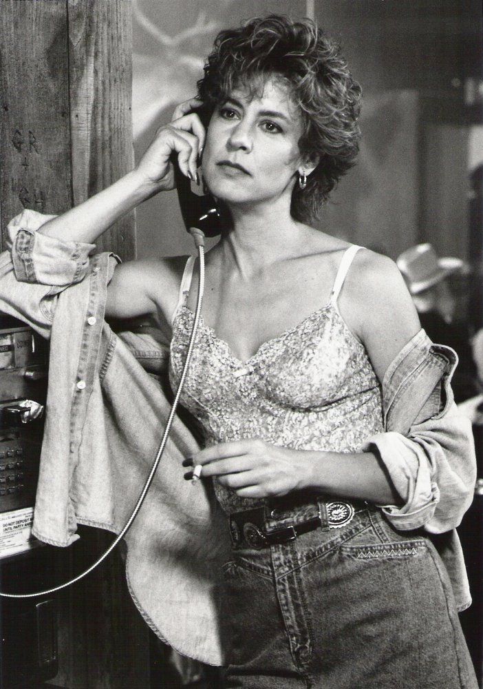 an old photo of a woman talking on the phone and holding a jacket over her shoulder