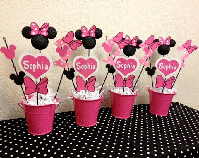 minnie mouse cupcakes are arranged in pink and black polka dot cups with name tags on them