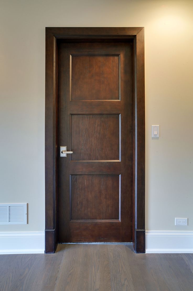 an empty room with a wooden door and hard wood flooring on the side wall