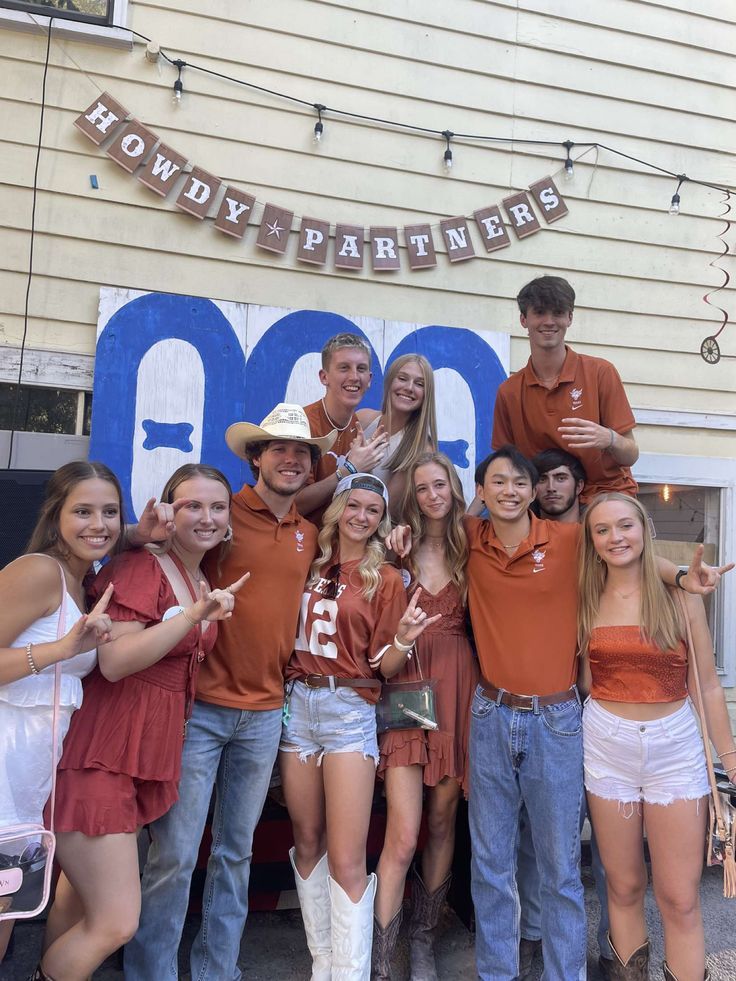 a group of young people standing next to each other in front of a building with a sign