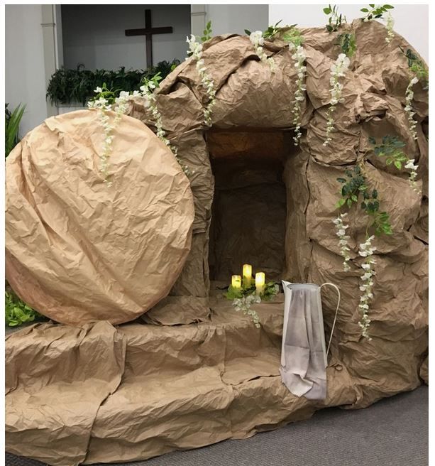 there is a fake rock structure with candles in the center and greenery around it