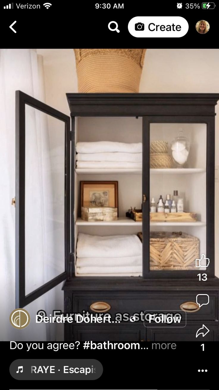 an open cabinet with towels and other items in it on the bottom shelf next to a window