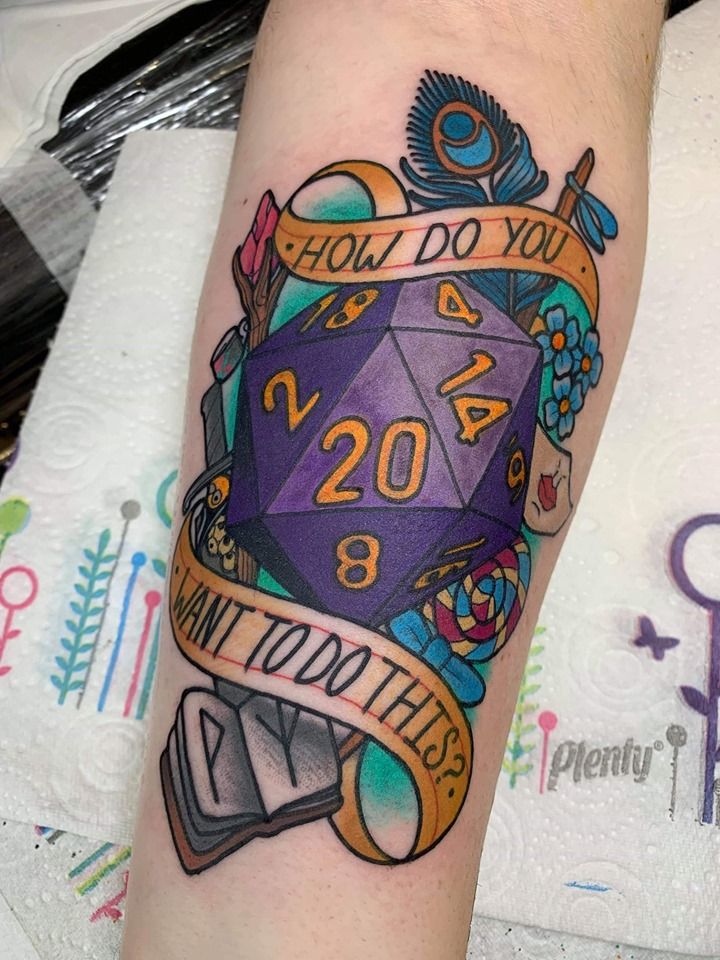 a tattoo on the arm of a person with a purple dice and ribbon around it