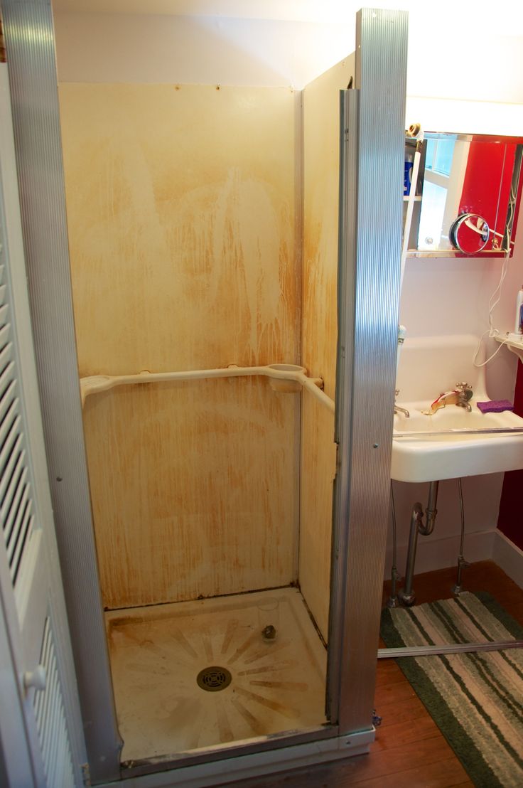 an open shower door in a bathroom next to a sink and bathtub with no curtain