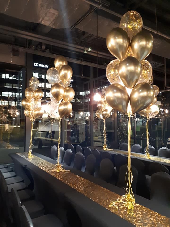 gold balloons and streamers are hanging from the ceiling