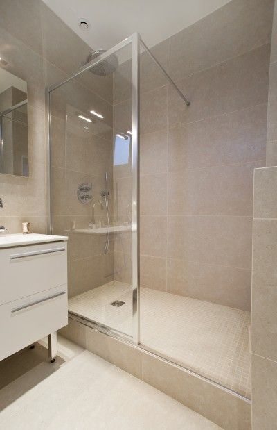 a bathroom with a walk in shower next to a white sink and mirror on the wall