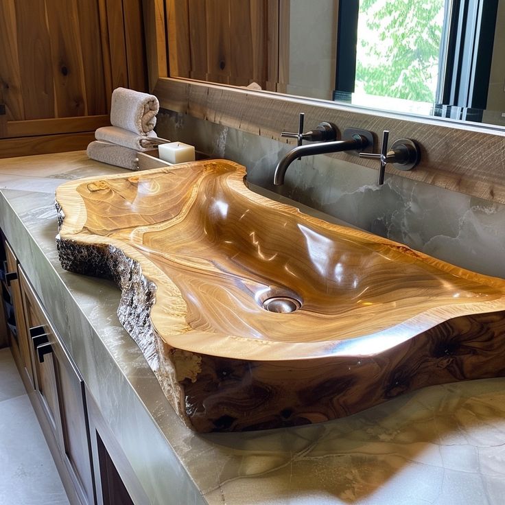 a bathroom sink made out of wood in front of a window with wooden cabinets behind it