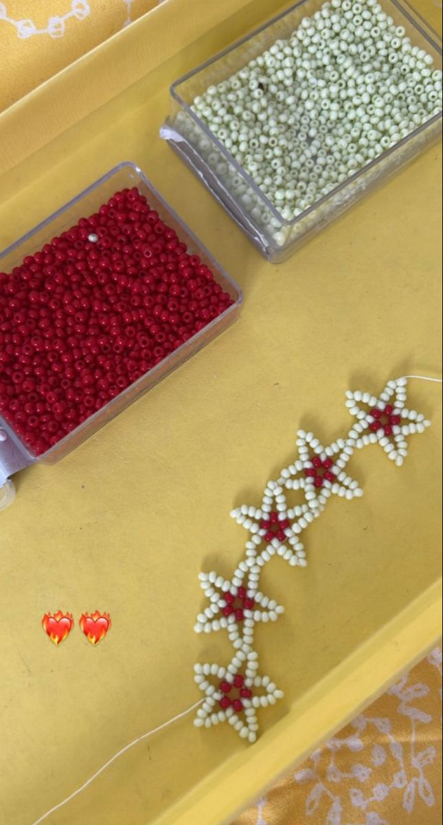 three plastic containers filled with beads on top of a yellow table covered in white and red decorations