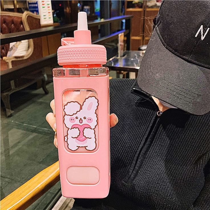 a person holding up a pink water bottle with a cartoon character on the front and side