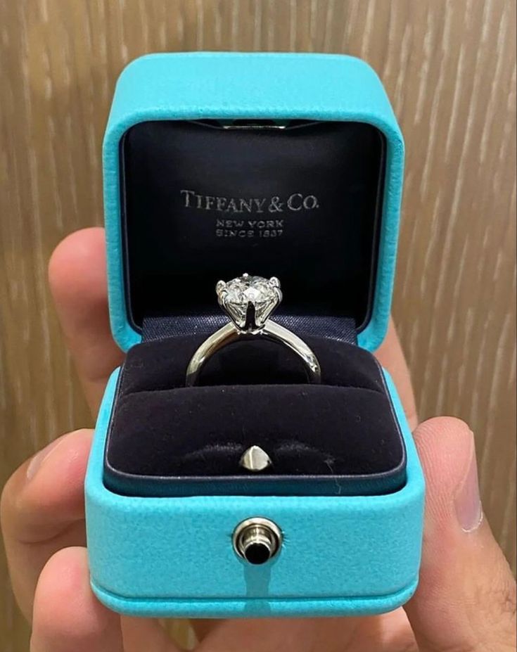 a person holding a ring in a blue box