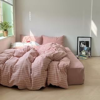 an unmade bed in a bedroom with pink comforter and pillows on the floor