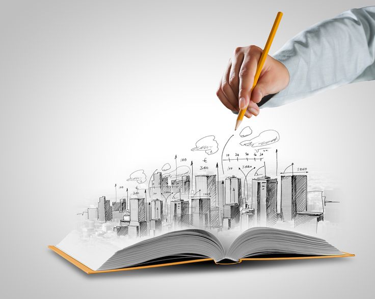 a person holding a pencil and drawing on an open book with buildings in the background