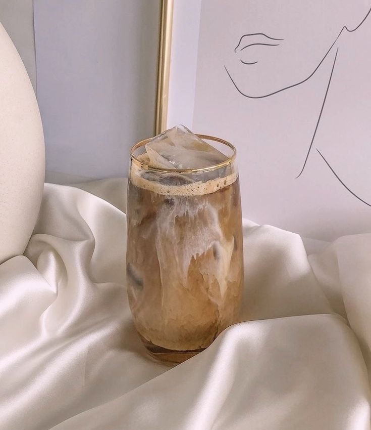 a glass jar sitting on top of a white cloth next to a framed drawing with a woman's face