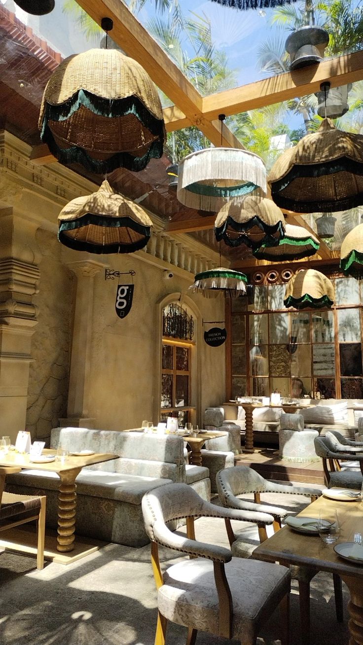 an outdoor dining area with tables and umbrellas hanging from the rafters over it