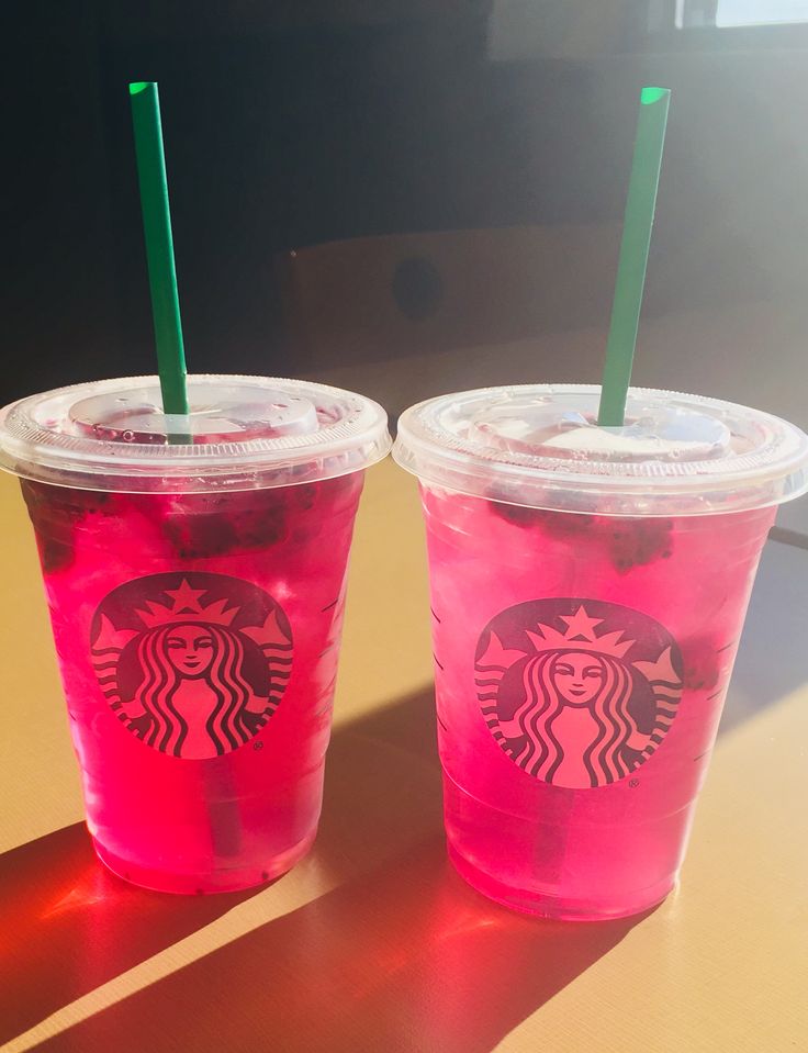 two plastic cups with straws sitting on a table