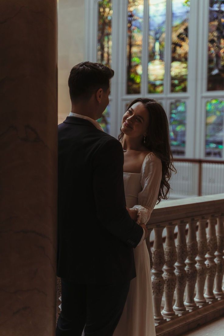 a man and woman standing next to each other in front of a building with stained glass windows