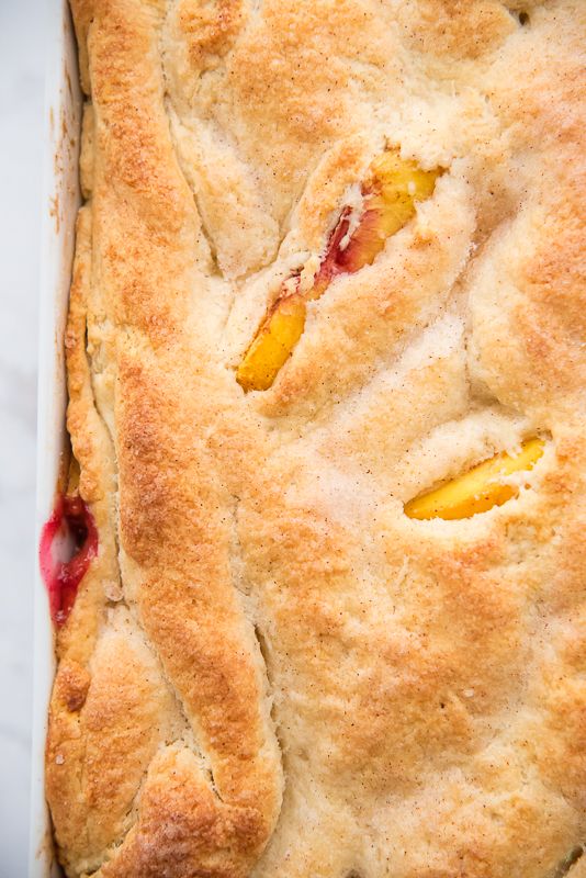 a close up of a pie in a pan with fruit on the top and one slice missing