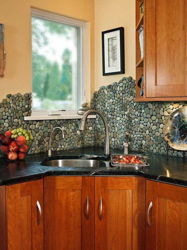 a kitchen with wooden cabinets, black counter tops and a stone wall behind the sink