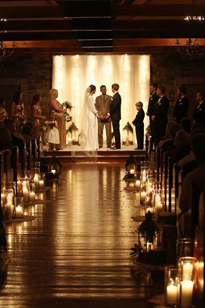 a bride and groom standing at the end of their wedding ceremony with candles in front of them