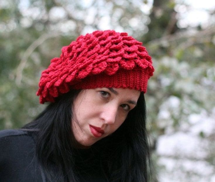 a woman with long black hair wearing a red knitted hat and looking at the camera