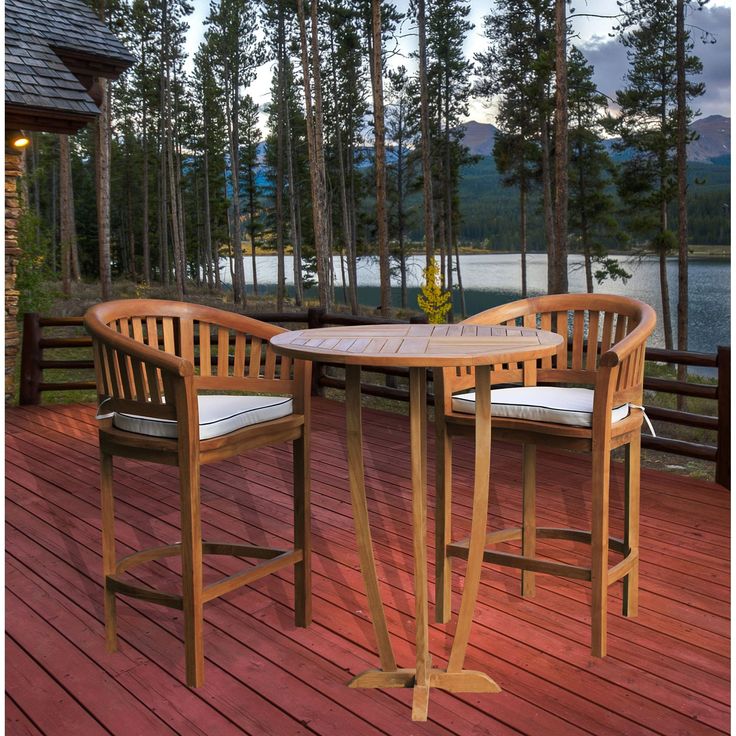 an outdoor table and chairs on a deck with trees in the backgroung