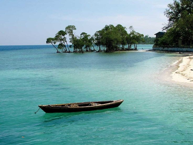 a small boat floating on top of a body of water next to an island in the ocean