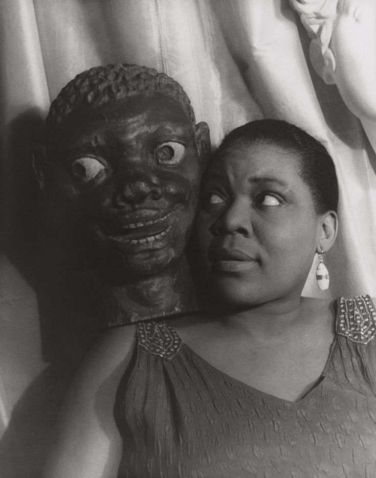 a woman standing next to a creepy mask