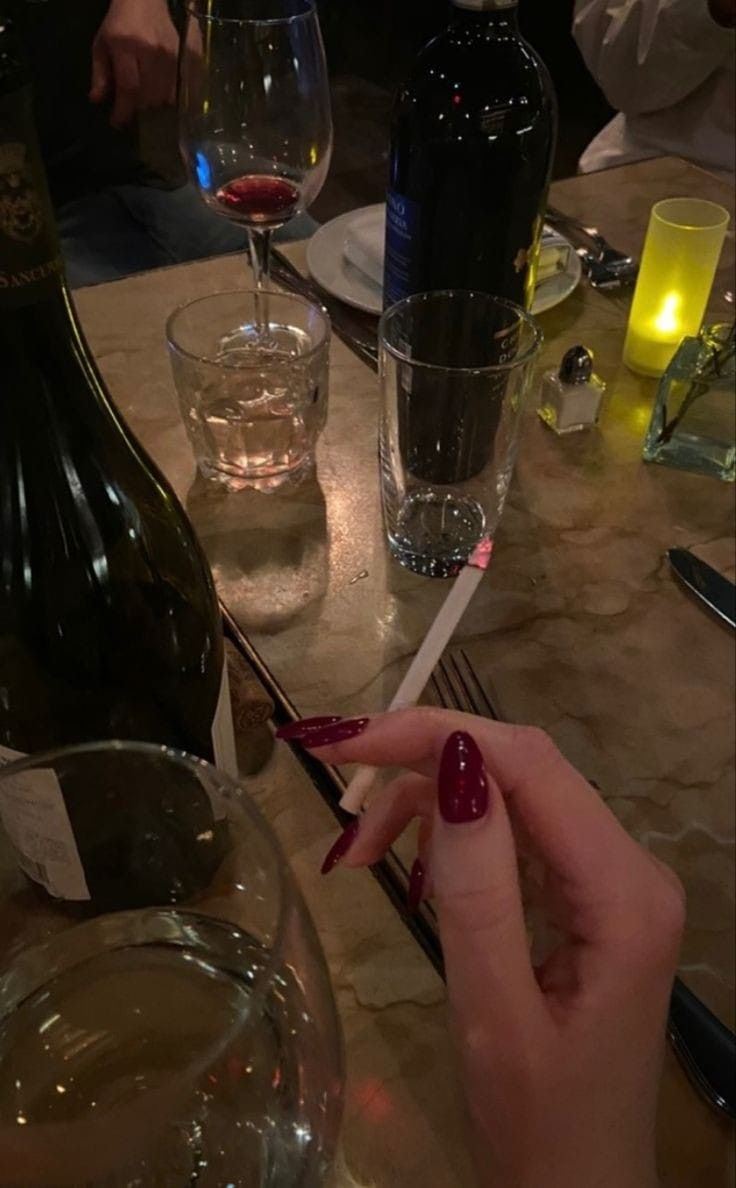 a woman sitting at a table with some wine glasses