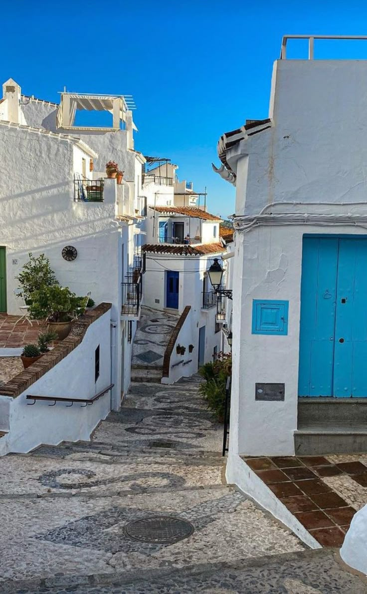 an alley way with white buildings and blue doors