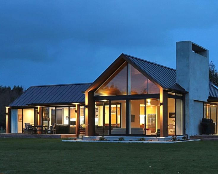 a modern house lit up at night with the lights on and windows open to let in light