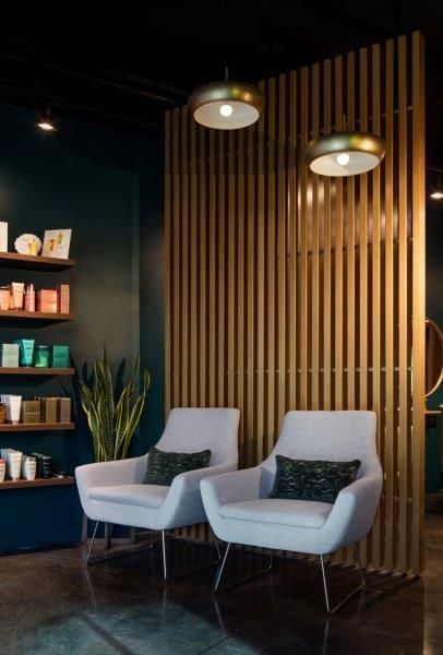 two white chairs sitting in front of a wooden wall with shelves on the opposite side